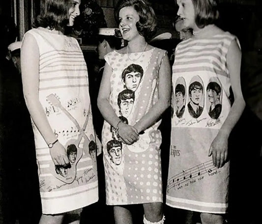 3 girls wear paper dresses with images of the band The Beatles printed on them