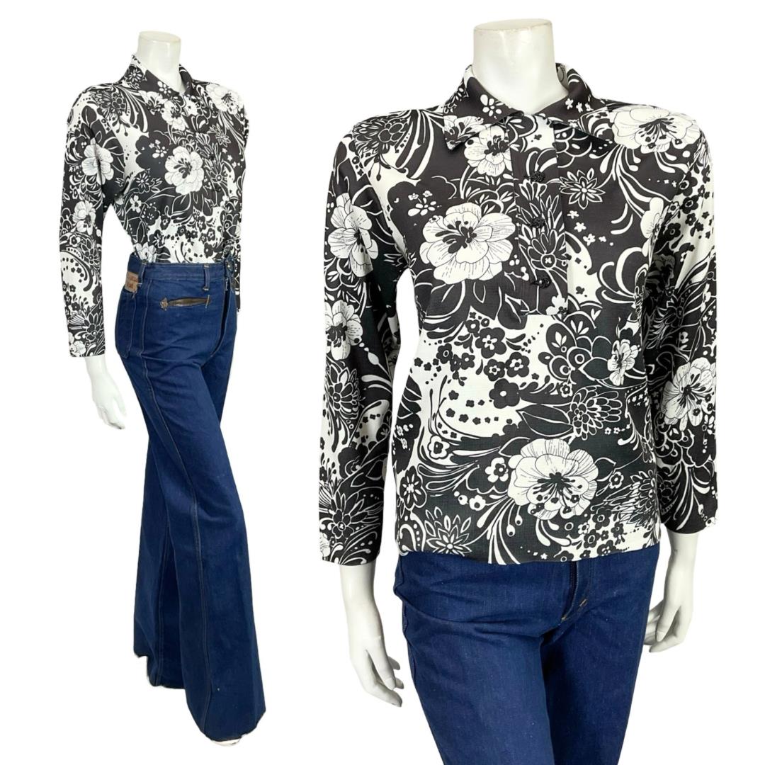 Mannequin wears a 60s 70s black and white floral printed dagger collar shirt with blue flared jeans. 