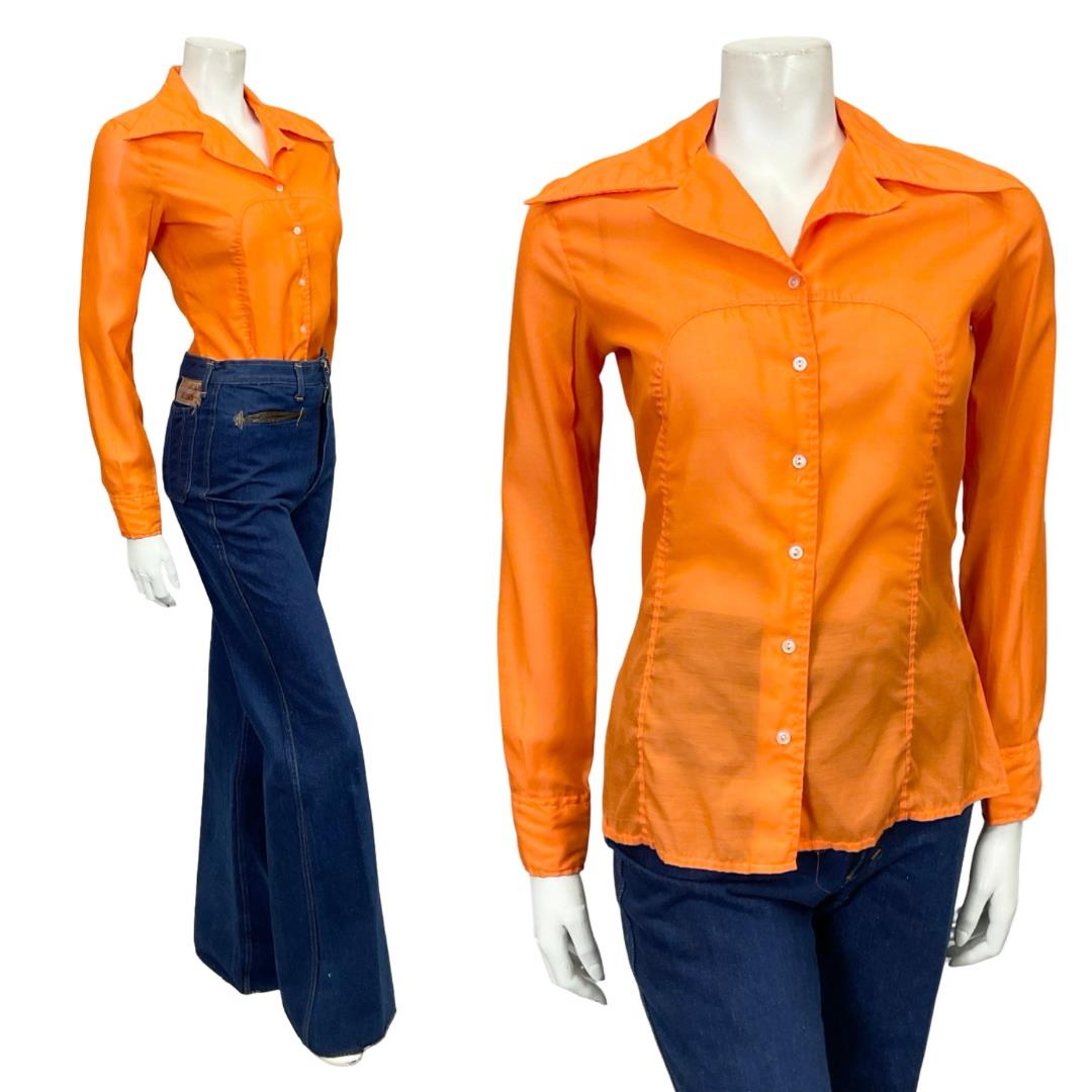 Mannequin wears a 60s 70s bright orange space age mod dagger collar shirt with blue flared jeans. 