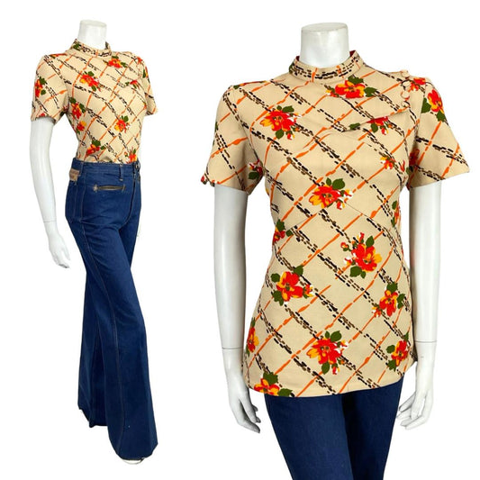 Mannequin wears a 60s beige and orange floral grid print short sleeve mod blouse with blue flared jeans. 