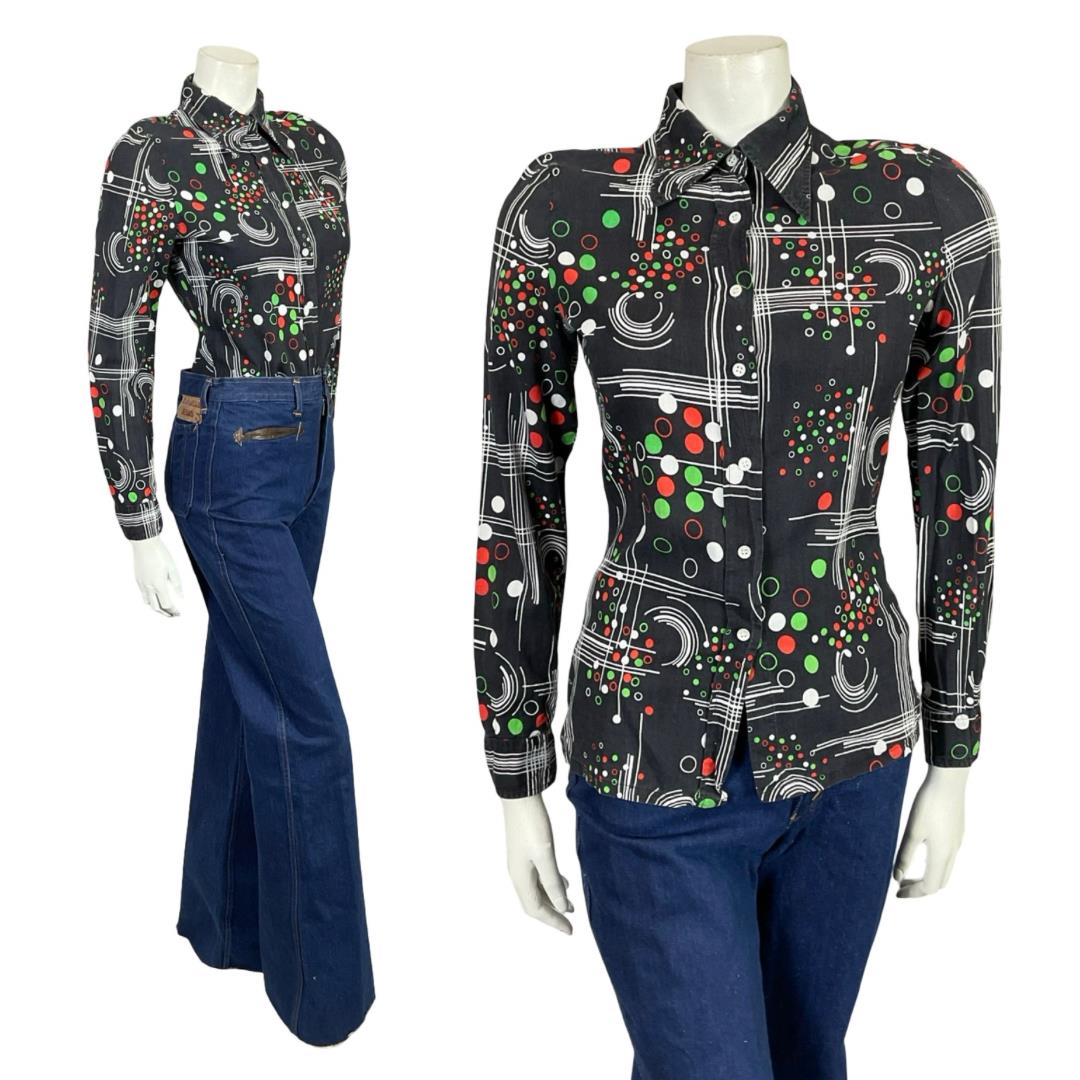 Mannequin wears a 60s 70s black green and white geometric dotty dagger collar shirt with blue flared jeans. 