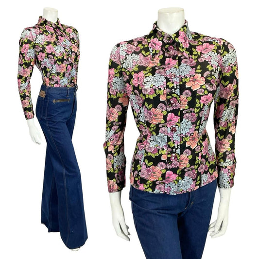 Mannequin wears a black blue and pink floral mod 60s 70s dagger collar shirt with blue flared jeans. 