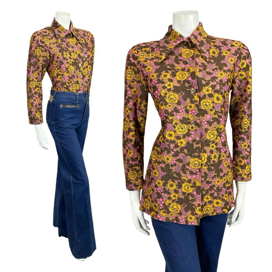 Mannequin wears a 60s 70s brown pink and yellow floral print dagger collar shirt with blue flared jeans. 