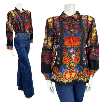 Mannequin wears a 60s 70s black red and blue psychedelic floral print dagger collar blouse with blue flared jeans. 