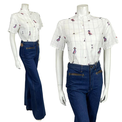 Mannequin wears a 60s 70s white and purple bird print mandarin collar shirt with blue flared jeans. 