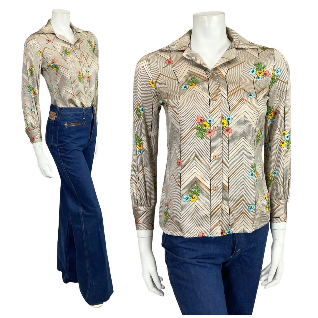 Mannequin wears a beige and black chevron floral print dagger collar 60s 70s shirt with blue flared jeans.