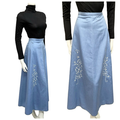Mannequin wears a 70s light blue denim skirt with white floral embroidery with a black turtleneck