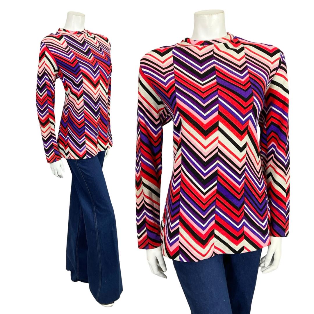 Shrinking Violets Vintage 60s 70s purple red white and black chevron zig zag blouse on a mannequin wearing blue flared jeans