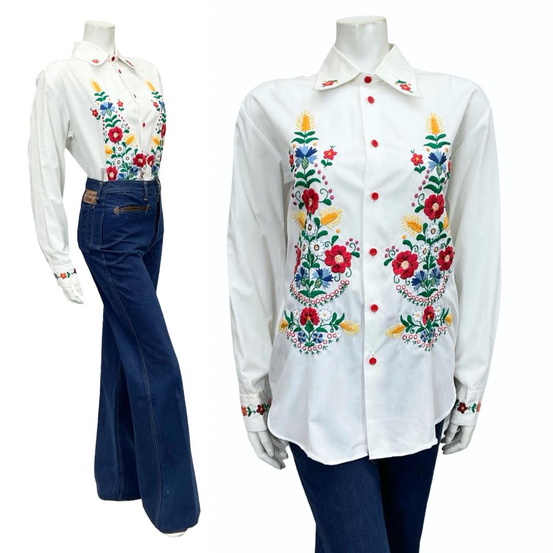 Shrinking Violets Vintage 60s 70s white floral and wheat harvest folk embroidery shirt on a mannequin wearing blue flared jeans