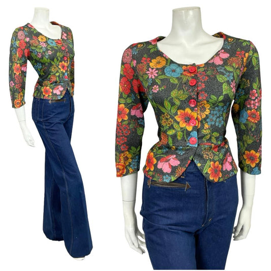 Mannequin wears a 60s 70s glittery black floral lurex peplum blouse with blue flared jeans 
