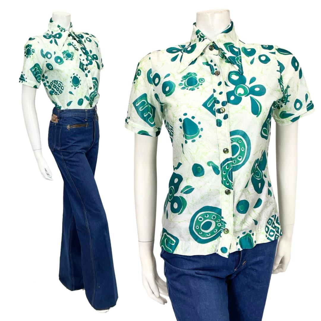 Shrinking Violets Vintage 60s 70s white and green psychedelic geometric short sleeved dagger collar shirt n a white mannequin wearing blue flared jeans 