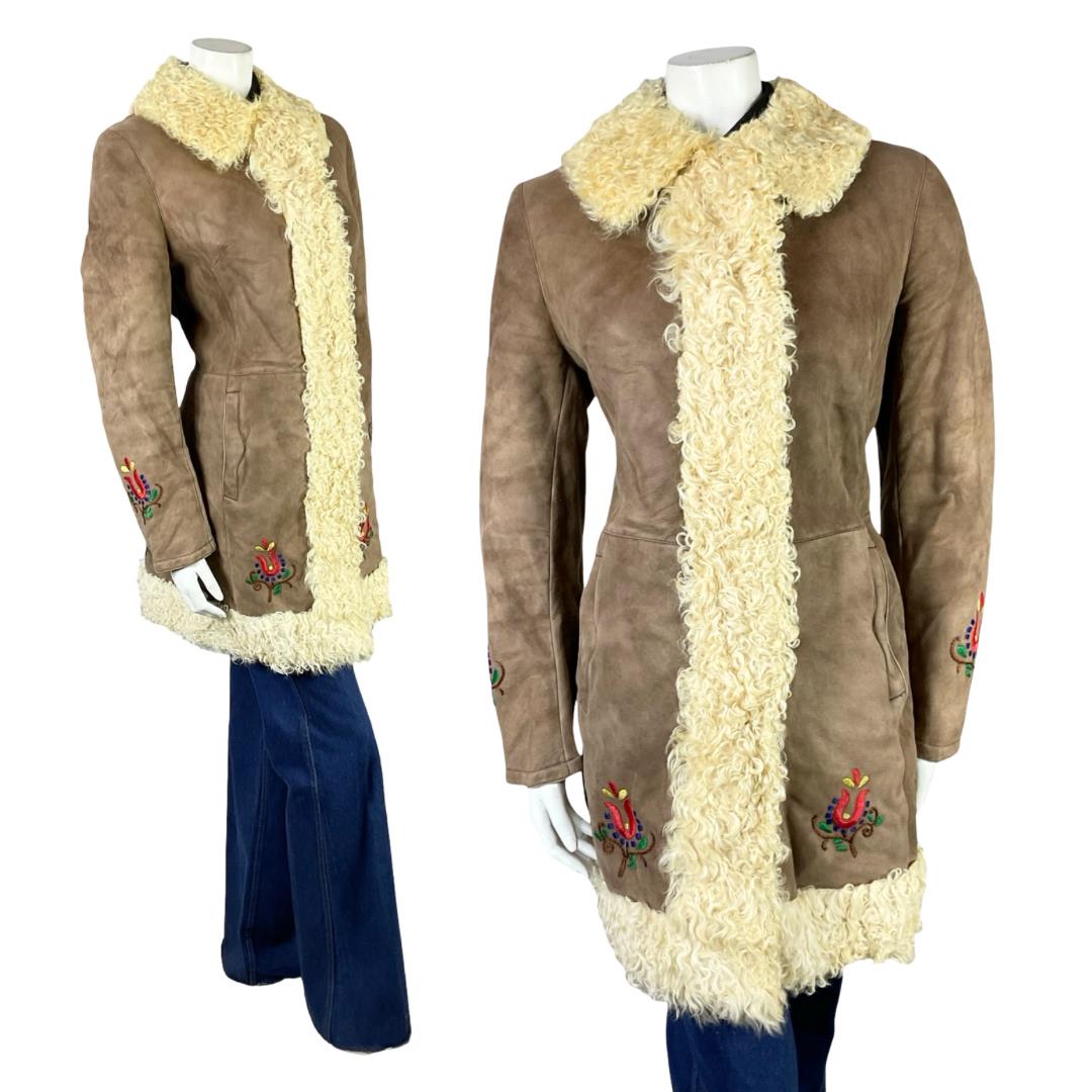 Shrinking Violets Vintage 60s 70s brown suede cream shearling with folk floral embroidery on a white mannequin wearing blue flared jeans 