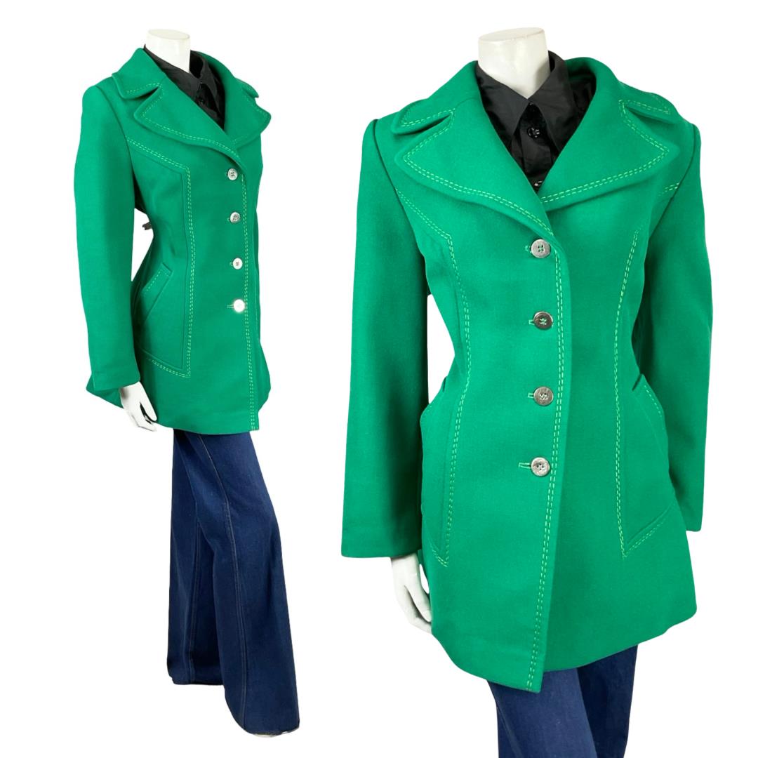 Shrinking Violets vintage 60s 70s mod green coat with contrast stitching on a white mannequin wearing blue flared jeans 