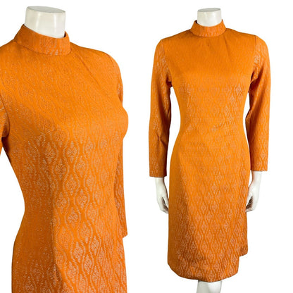 Mannequin wears a bright orange and silver geometric weave mod shift dress with long sleeves and a funnel neck.