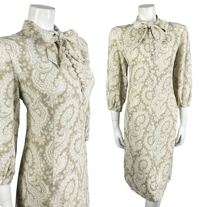 Mannequin wears a vintage 60s 70s beige and white psychedelic long sleeve pussybow shift dress.
