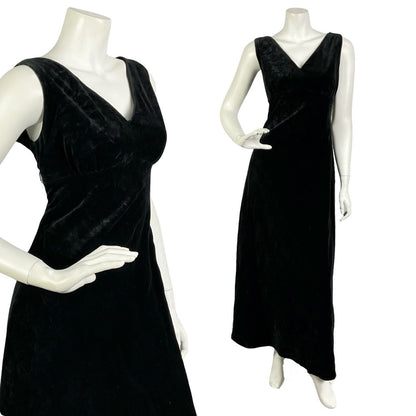 Mannequin wears a vintage 60s 70s sleeveless black velvet empire maxi dress with a plunging neckline. 