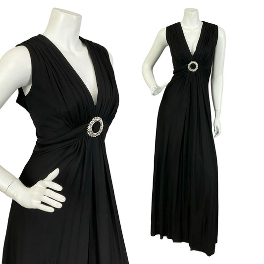 Mannequin wears and all black, ruched, sleeveless maxi dress with an O-ring diamanté decoration in the centre of the waistband. 