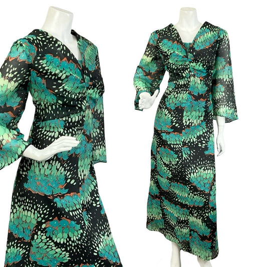 Mannequin wears a black and green floral plunge V neck maxi dress with cropped bell sleeves. 