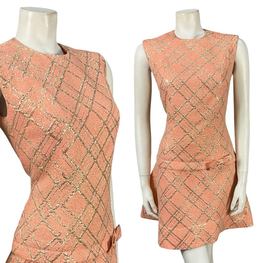 Mannequin wears a salmon pink and gold lurex plaid sleeveless mini dress with a dropped waistline. 