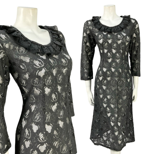 Mannequin wears an all black lace mini party dress, with cropped sleeves and a ruffled round neckline. 
