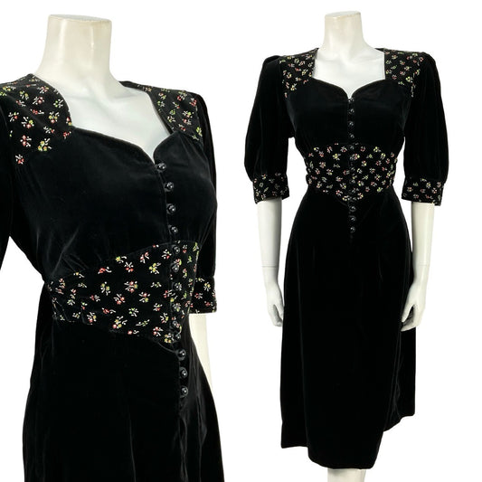 Mannequin wears a black velvet puff sleeve, sweetheart midi dress with a floral print waistband. 