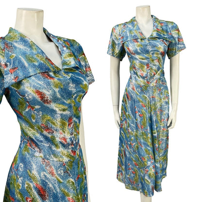 Mannequin wears a vintage 60s 70s lurex handmade shirt dress with an abstract lurex print in blue green and red. 