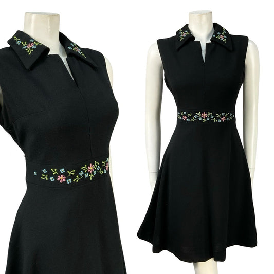 Mannequin wears a black wool sleeveless mini dress with a floral waistband. 