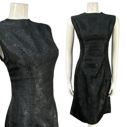 Mannequin wears a vintage 60s sleeveless little black dress with a floral damask print. 
