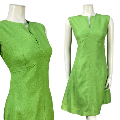 Mannequin wears a vintage 60s empire sleeveless mini dress made from a green, glittery lurex. 