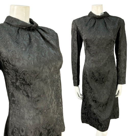 Mannequin wears a vintage 60s long sleeve black mini dress with a glittery Aztec damask pattern. 