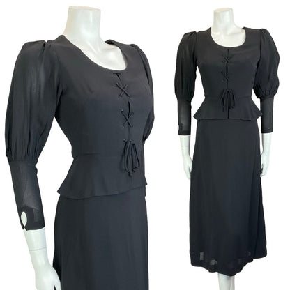 Mannequin wears black vintage 60s 70s medieval revival midi dress with mutton sleeves and a peplum waist