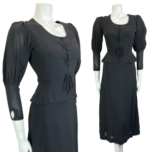 Mannequin wears black vintage 60s 70s medieval revival midi dress with mutton sleeves and a peplum waist