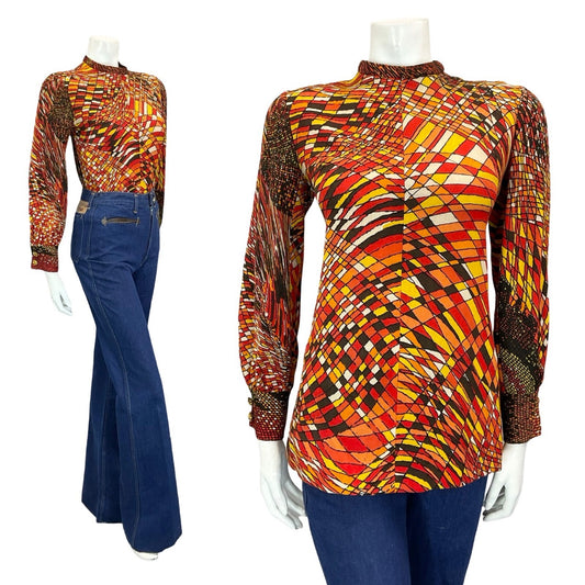 mannequin wears blue flared jeans with a psychedelic brown, orange, red and white geometric long sleeve top