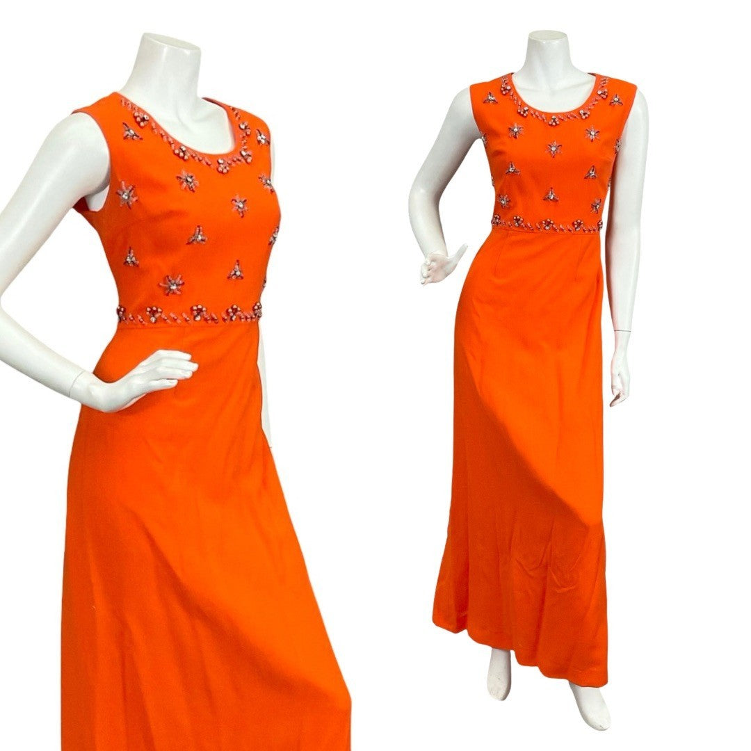 Mannequin wears a sleeveless bright orange wool maxi dress with a star beaded embellished bodice. 