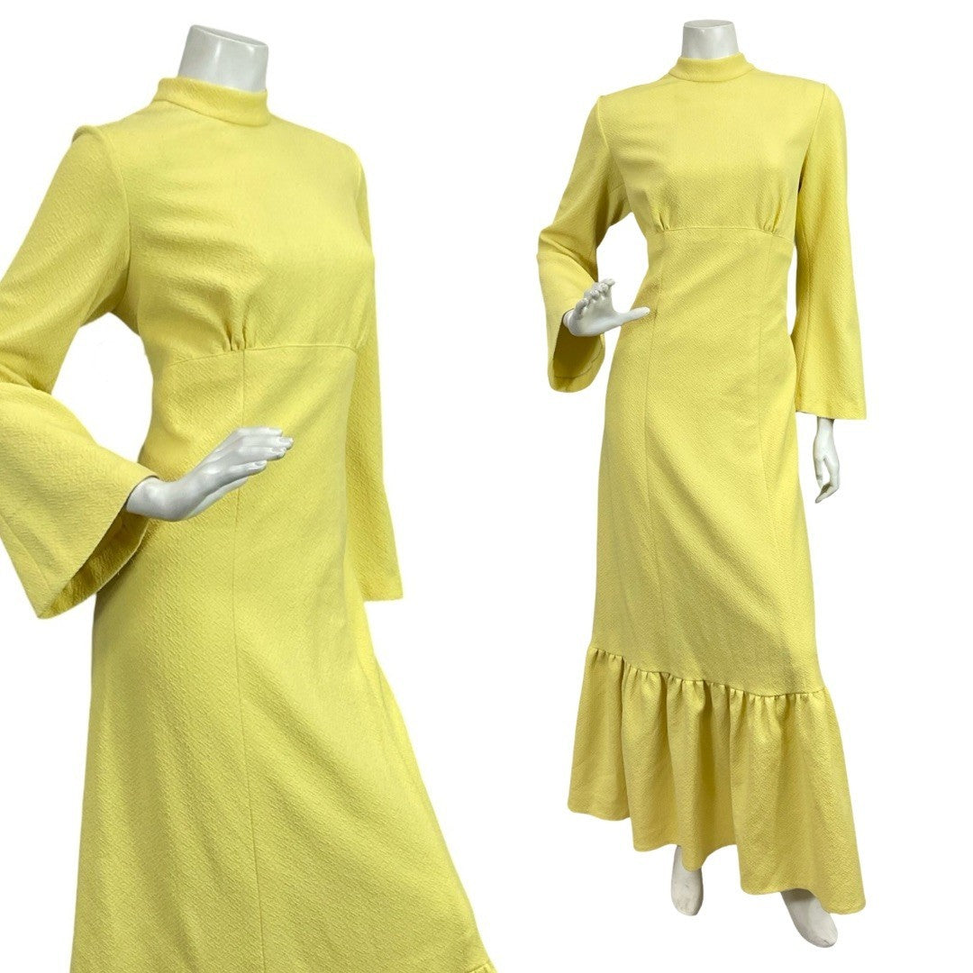 Mannequin wears a 60s 70s bright yellow bell sleeve maxi dress with a funnel neck and ruffled hemline. 