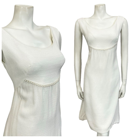 Mannequin wears a 60s sleeveless empire bridal mini dress with shimmery pearl beaded embellishment.