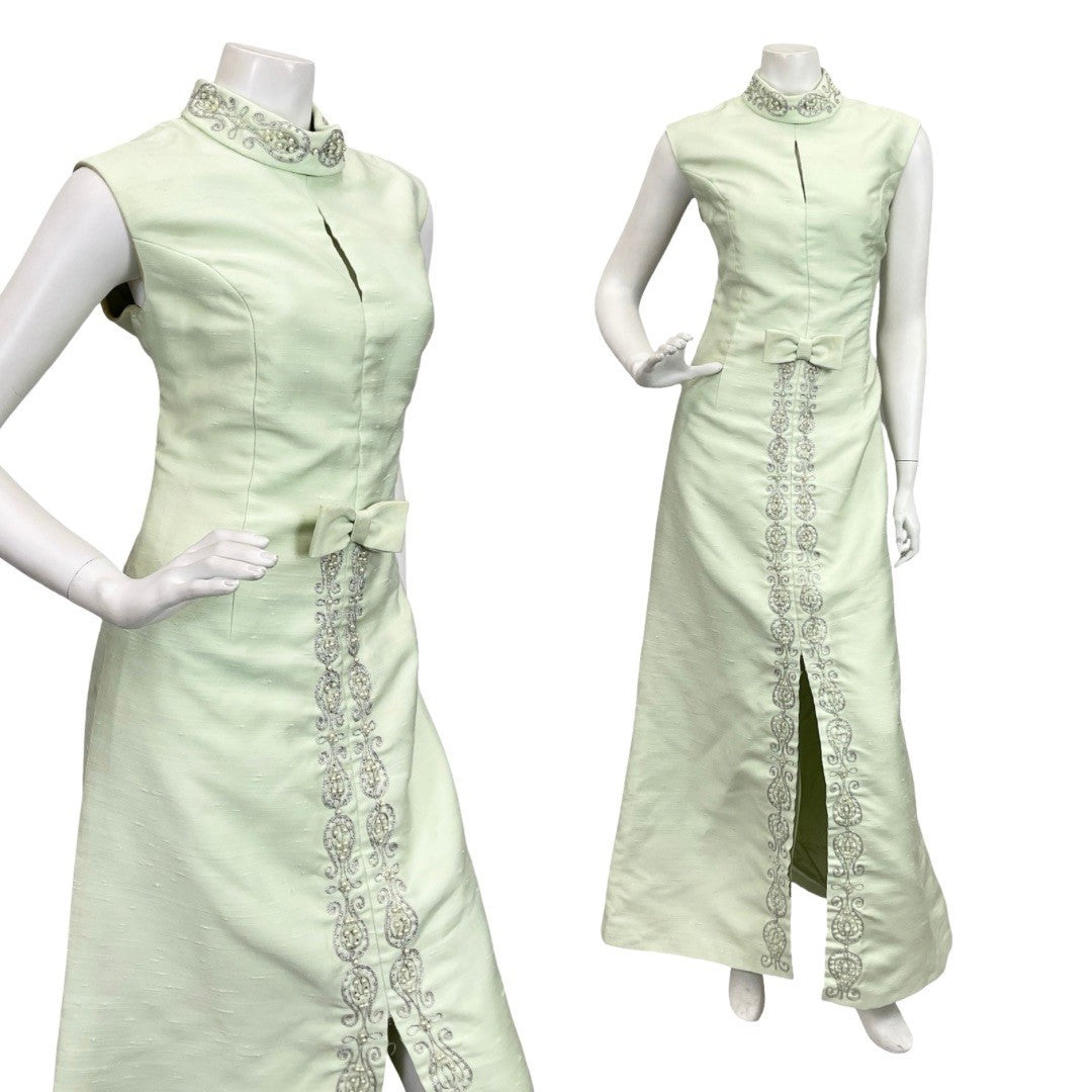 Mannequin wears a pastel green sleeveless keyhole maxi dress with silver paisley and pearl embellishment. 