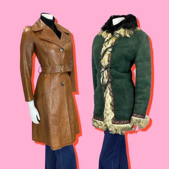 The mannequin on the left is wearing blue bell bottom jeans and a long light brown leather belted trench coat. The mannequin on the right is wearing a green suede afghan shearling coat with cream fur trim