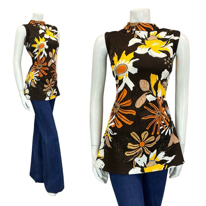 mannequin wears blue flared jeans with a brown tunic patterned with orange and yellow flowers